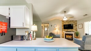 A kitchen with a white island, blue cabinets, and a dining area with a gray sofa. - 7 Mi to the Hammocks Beach: 3 BD Near Camp Lejeune (Hubert)