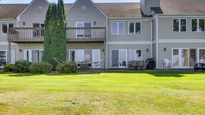 Ein zweistöckiges Wohngebäude mit Balkon, Rasen und Gartenmöbeln.