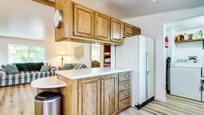 Une cuisine compacte avec des meubles en bois, un réfrigérateur blanc et un lave-linge encastré.