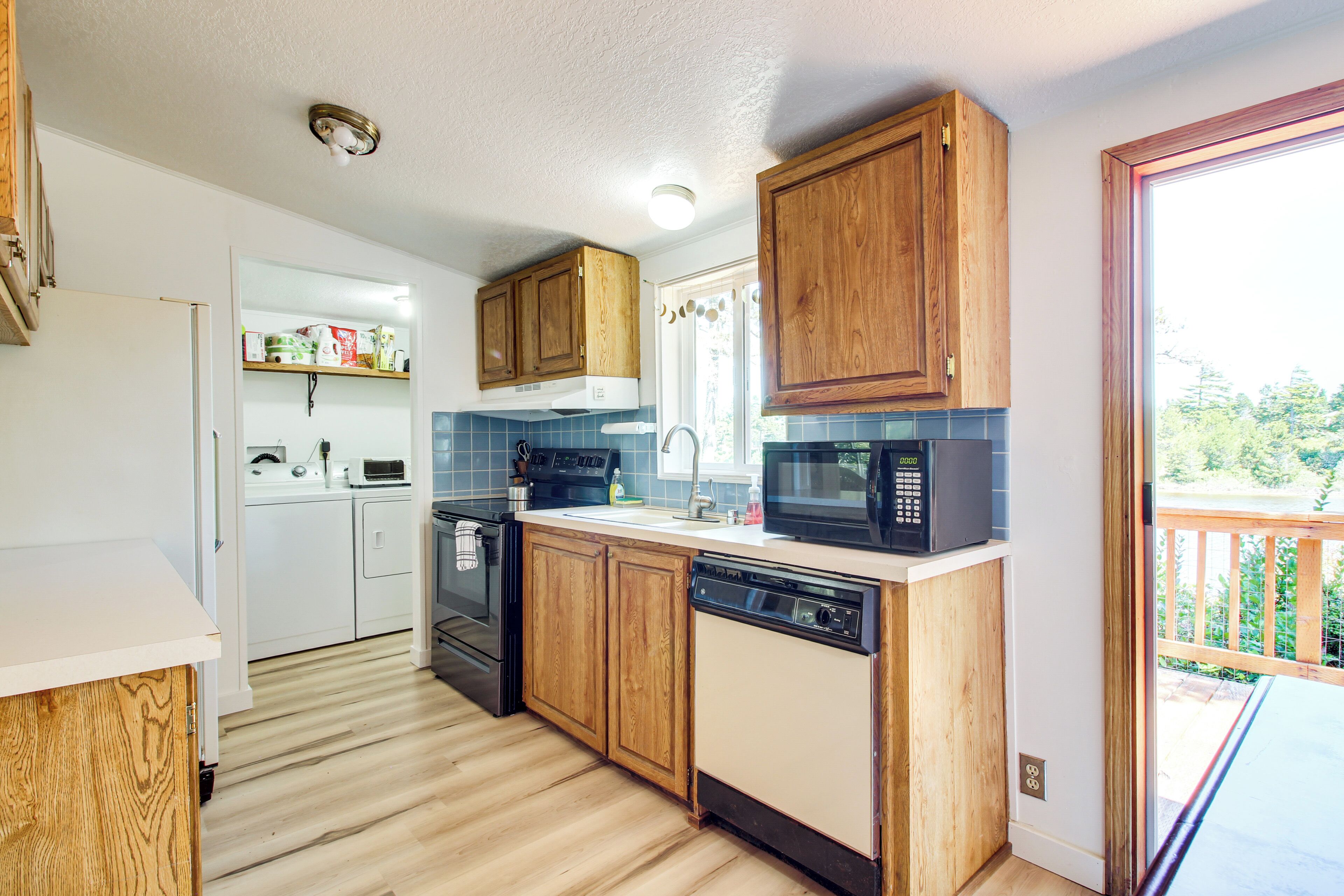 A compact kitchen with wooden cabinets, a dishwasher, a microwave, and a built-in oven.