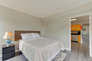 A bedroom with a bed, nightstand, lamp, and a view into the kitchen. - Close to Hospital & White Marsh! Rosedale Townhome (Rosedale)