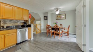 A modern kitchen with wooden cabinets, stainless steel appliances, and a dining area with wooden chairs and a table. - Close to Hospital & White Marsh! Rosedale Townhome (Rosedale)