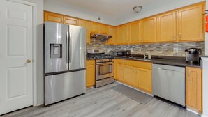 A modern kitchen with stainless steel appliances, wooden cabinets, and a tiled backsplash. - Close to Hospital & White Marsh! Rosedale Townhome (Rosedale)