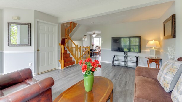 A living room with a staircase, a green vase with flowers, a television, and a sofa. - Close to Hospital & White Marsh! Rosedale Townhome (Rosedale)