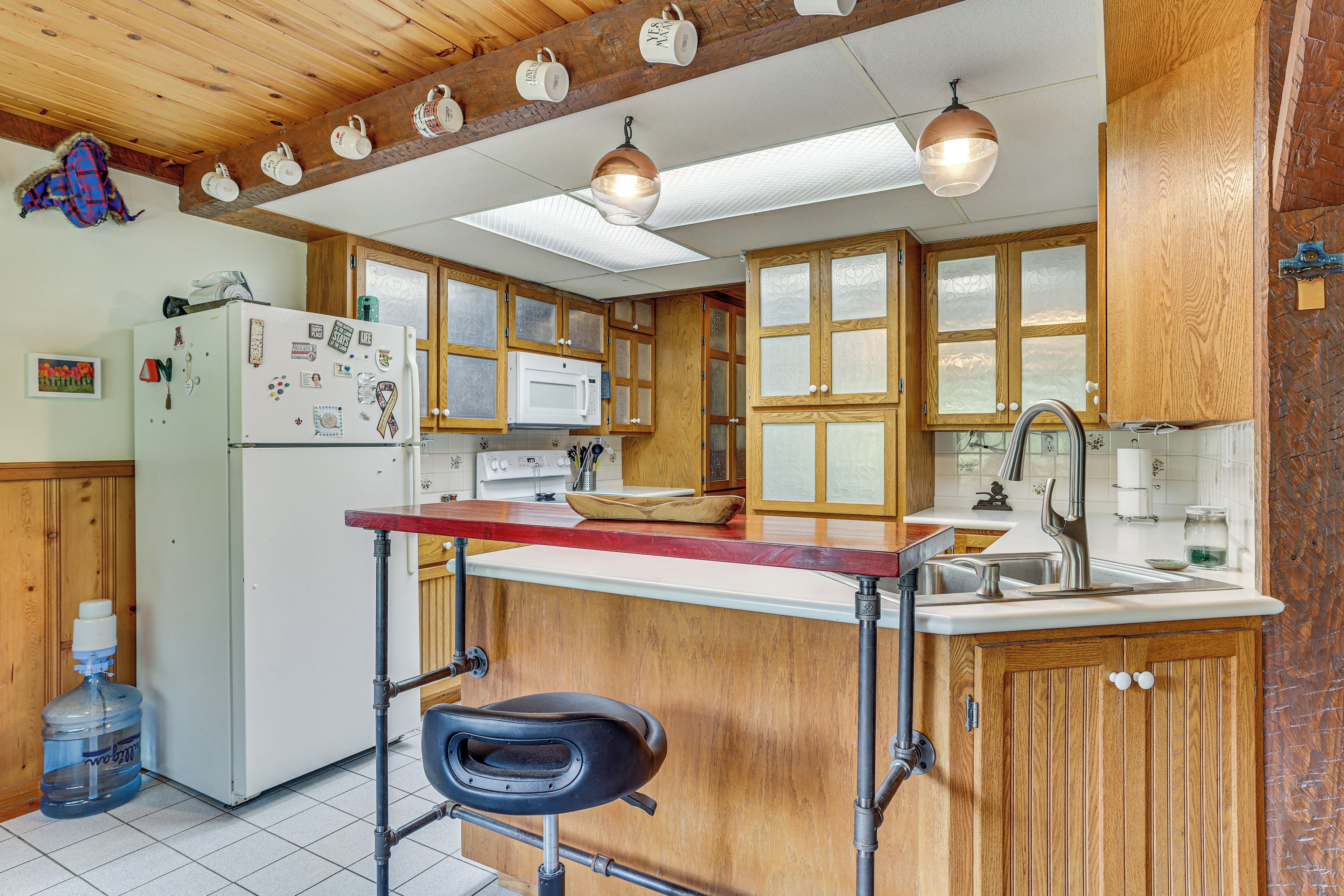 Una cocina con armarios de madera, un refrigerador, un microondas y un lavamanos.