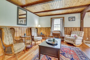 A cozy living room with wooden floors, a large mirror, a rocking chair, a tufted armchair, and a coffee table with a tray. - Near Mississippi River! Countryside Family Retreat (Eastman)