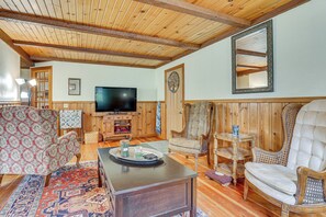A cozy living room with wooden beams, a television, patterned chairs, and a coffee table. - Near Mississippi River! Countryside Family Retreat (Eastman)