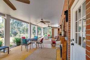A covered patio with a dining table and chairs, a ceiling fan, and a brick wall. - Screened Porch: Peaceful Country Escape in Ashford (Ashford)