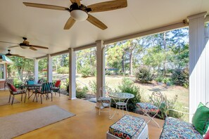 A covered patio with ceiling fans, outdoor furniture, and a view of a landscaped garden. - Screened Porch: Peaceful Country Escape in Ashford (Ashford)