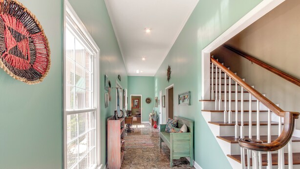 A hallway with a staircase, a bench, and a decorative wall hanging. - Screened Porch: Peaceful Country Escape in Ashford (Ashford)