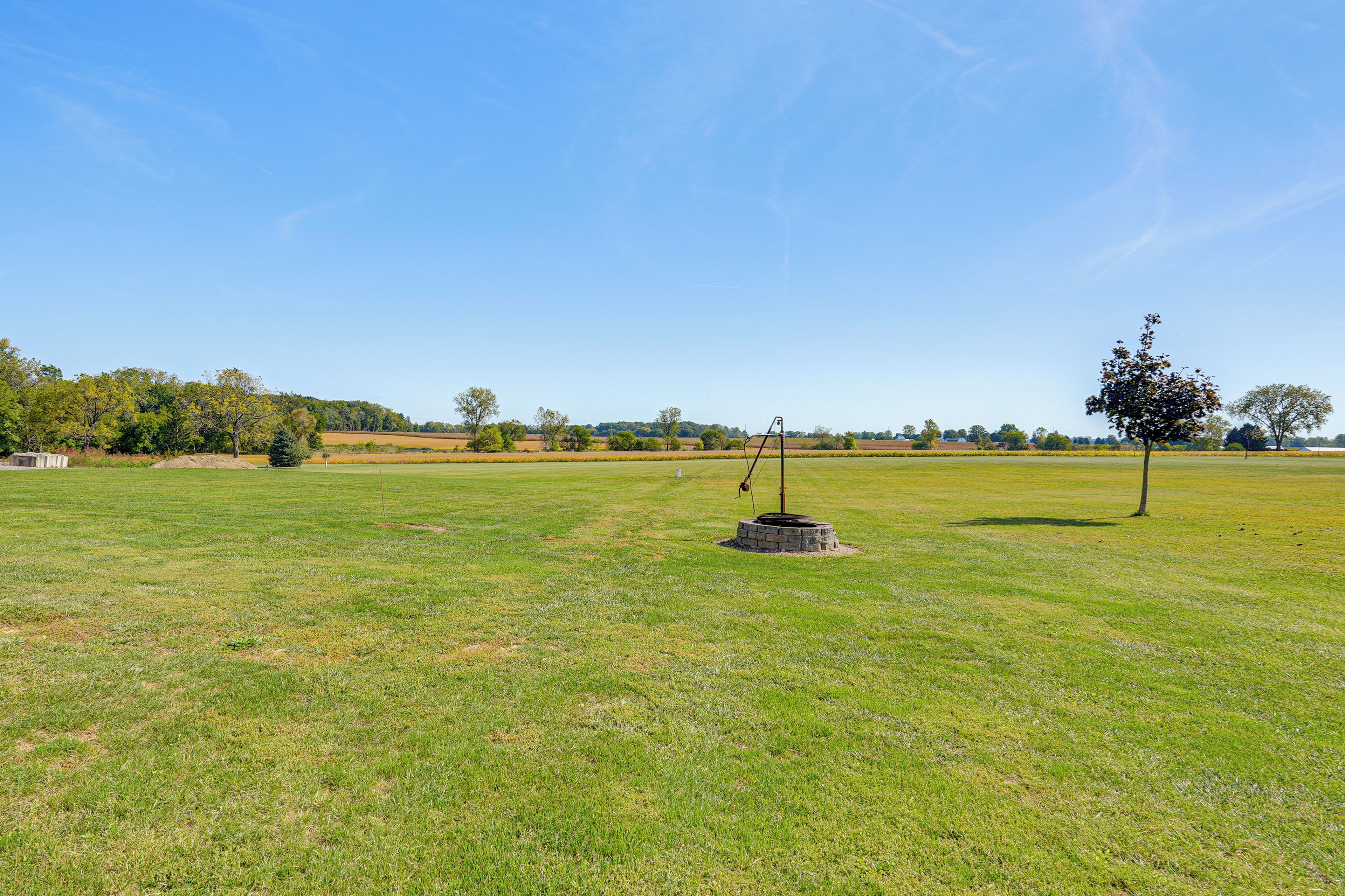 A grassy field with a stone structure and a tree.