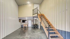 A spacious industrial-style interior with a central staircase and a door leading to a smaller enclosed area. - 1 Mi to Main St! Family Farmhouse in West Unity (West Unity)