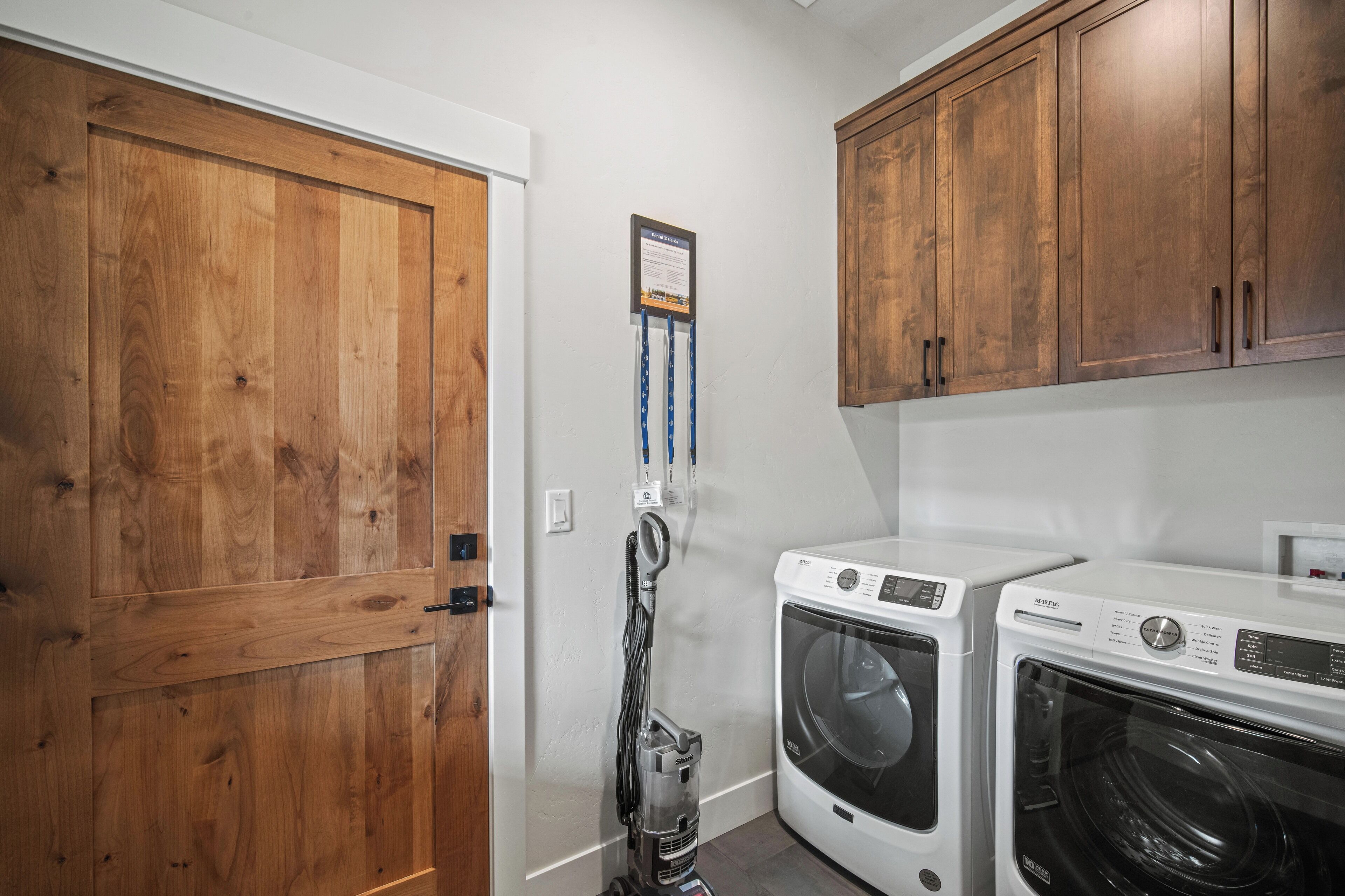 A laundry room with wooden cabinets, a washing machine, and a dryer.