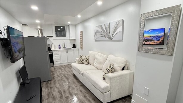 Un salon moderne avec un canapé, un téléviseur et un écran plat fixé au mur.