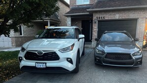 Deux voitures sont garées devant une maison qui a un garage.