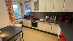 A compact kitchen with white cabinets, a built-in oven, a microwave, and a coffee maker. - EcoLodge2 (Oesterdeichstrich)