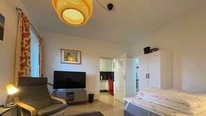 A modern hotel room with a TV, a sofa, a bed, and a dining area. - EcoLodge2 (Oesterdeichstrich)