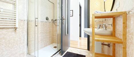 A modern bathroom with a glass-enclosed shower, a wooden vanity, and a white sink.