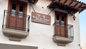A two-story building with a sign reading "Recanto das Libélulas Pousada" and a potted plant in the entrance. - Recanto das Libelulas pousada (Tiradentes)