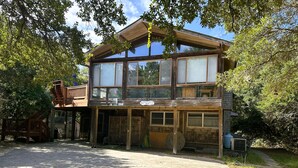 Une cabane en bois à deux étages, dotée d’un porche couvert et d’une cour clôturée.