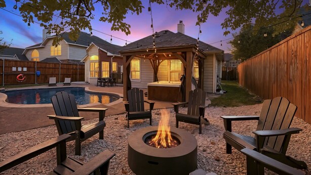 A backyard with a hot tub, Adirondack chairs, and a fire pit. - 5-BD/2-BA Vacation Retreat w/ Pool, Hot Tub & BBQ (Haltom City)