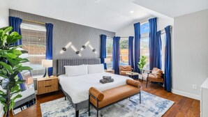 A modern hotel room with a large bed, a bench, a desk, and a chair. - 5-BD/2-BA Vacation Retreat w/ Pool, Hot Tub & BBQ (Haltom City)