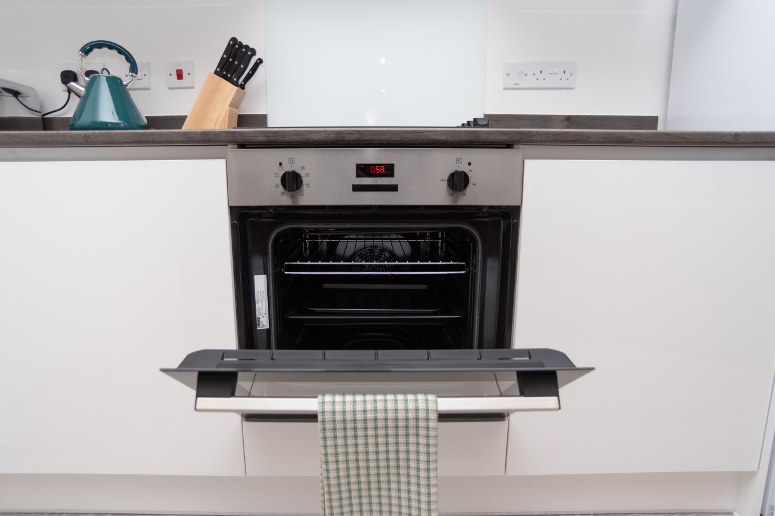 Une cuisine équipée d’un four, d’une bouilloire et d’un bloc à couteaux posé sur le plan de travail.