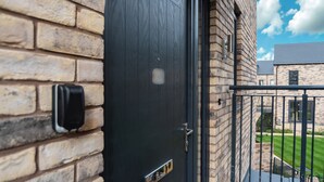 A brick building with a dark wooden door, a mailbox, and a small balcony with a metal railing.