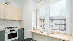 Une cuisine moderne équipée d’une cuisinière à gaz, d’un four et de chaises vertes.