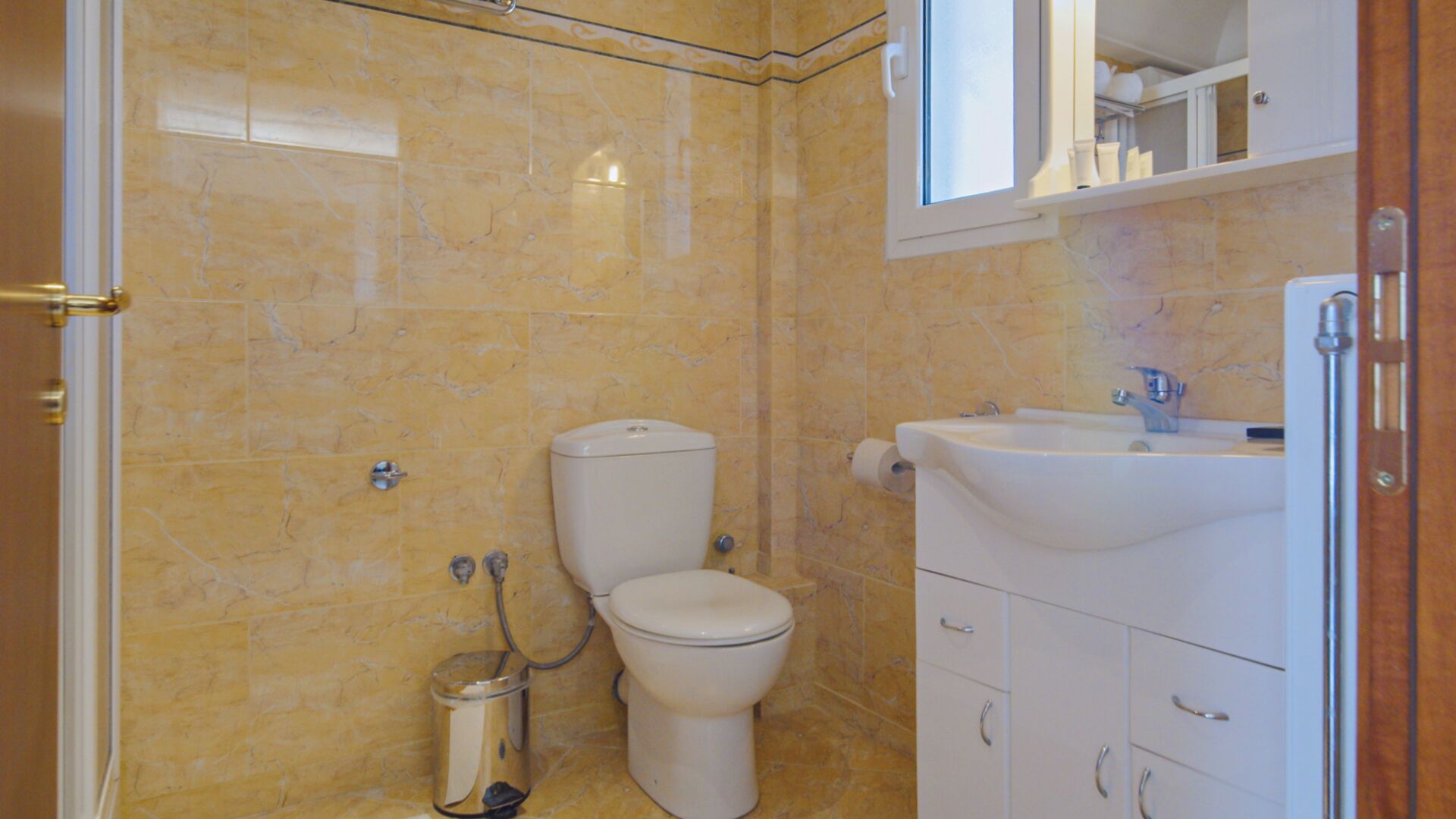 A bathroom with a toilet, sink, and cabinet.
