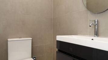 Une salle de bain moderne avec des toilettes, un lavabo et un miroir.