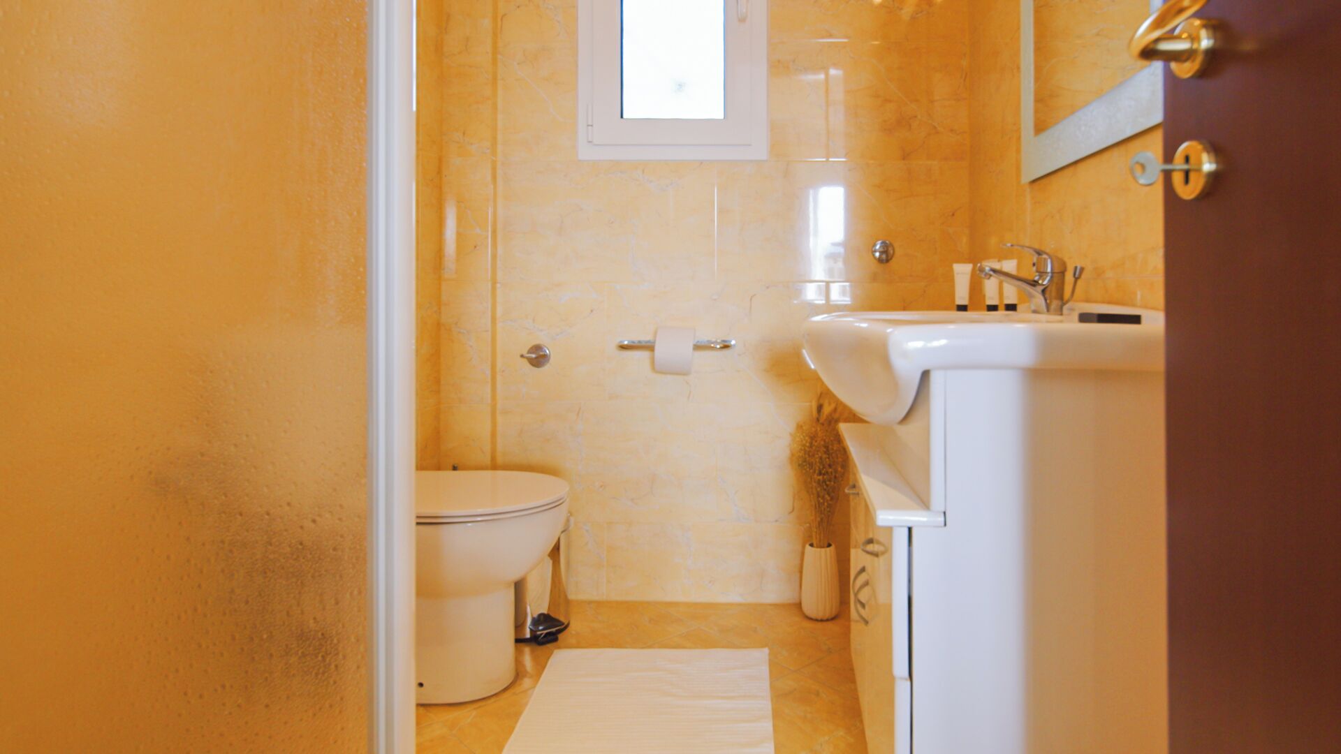 A bathroom with a toilet, a sink, and a small window.
