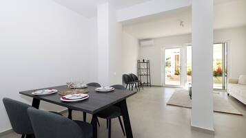 A modern dining area with a dark wooden table set for four, surrounded by grey chairs.