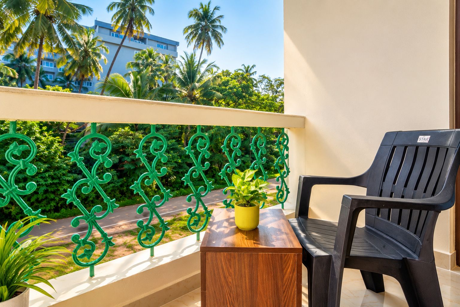 A balcony with a black plastic chair, a wooden table, and a yellow potted plant.
