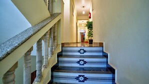 A staircase with marble steps and a handrail, leading to a landing with a potted plant. - The Coral Reef (Candolim)