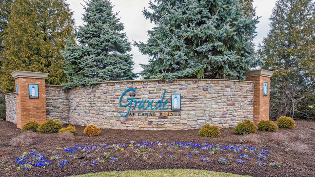 A stone wall with a sign for "The Grande" hotel, featuring a brick entrance and a flower bed in front. - Grande at Canal 14 For 6ppl (Rehoboth Beach)