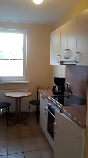 A small kitchen with a window, a table, two chairs, and a coffee maker.