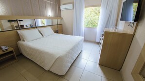 Una habitación de hotel con cama, mesita de noche y un pequeño escritorio con silla.