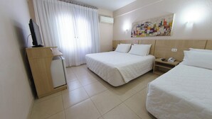 A hotel room with two beds, a desk with a computer, a small refrigerator, a telephone, and a painting on the wall. - Three Couple Rooms | Breakfast Included | Near Iguazu Waterfalls (Parana)