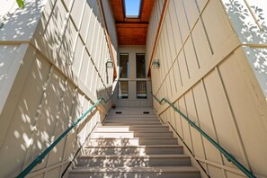 A narrow staircase with a skylight, wooden ceiling, and light-colored walls.