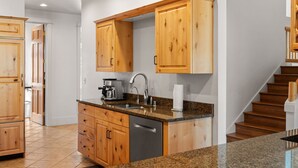 Una cucina moderna con mobili in legno, un piano di lavoro in granito e una lavastoviglie in acciaio inossidabile.
