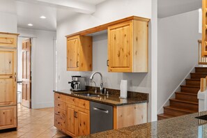 Una cocina moderna con armarios de madera, encimera de granito y lavavajillas de acero inoxidable.