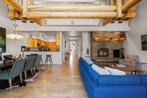 Amplia sala de estar con sofá azul, mesa de comedor de madera y chimenea de piedra.