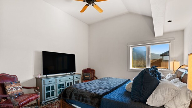 Una camera da letto con un letto, una televisione, una cassettiera e una finestra vista all'esterno.
