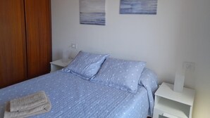 Ein Schlafzimmer mit einem Bett, Nachttischen, einem Holzschrank und zwei Wandbildern.
