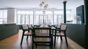 A modern dining area with a long table, multiple chairs, and hanging pendant lights.