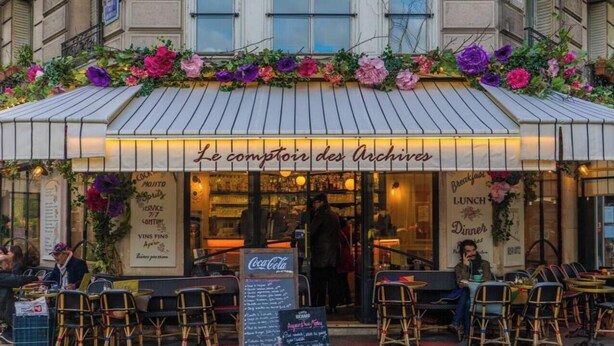 A restaurant named "Le comptoir des Archives" with outdoor seating and a menu board.