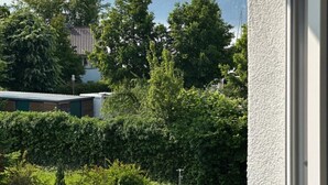 Een balkon met uitzicht op een groen landschap, bomen en een bergketen in de verte.