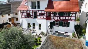Een herenhuis met twee verdiepingen, een rood tegeldak, witte muren en een balkon.
