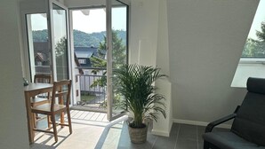 A room with a balcony, a potted plant, a dining table with chairs, and a sofa. - Apartment 'Ferienwohnung Seescheune' with Lake View and Wi-Fi (Bodman-Ludwigshafen)